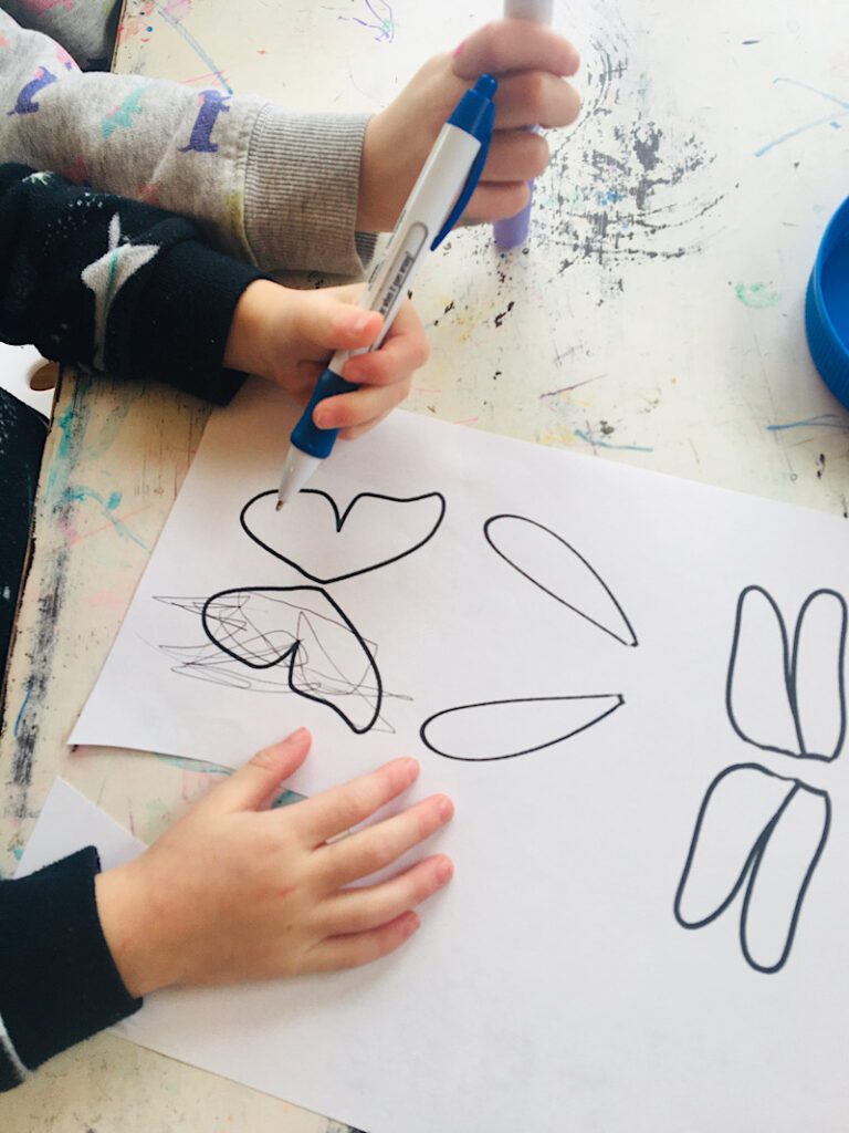 kids scribbling on a page with insect wing images